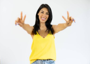 Gündelik kıyafetler giyen, gülen yüzlü, zafer işareti yapan güzel genç bir kadın. İki numara..