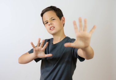 Kafkasyalı küçük bir çocuk günlük kıyafetler giyip avuçlarını hareket ettiriyor. Korkmuş ve iğrenç bir ifadeyle reddediyor. Dur ve yasakla.