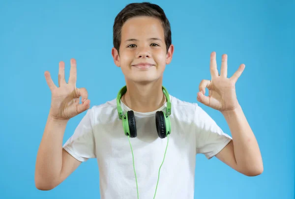 Νεαρό Χαμογελαστό Αγόρι Φορώντας Ακουστικά Εντάξει Σημάδι Πάνω Από Μπλε — Φωτογραφία Αρχείου