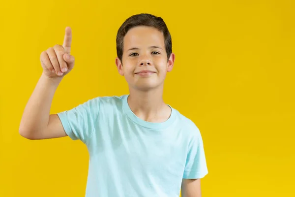 Zdjęcie Młodego Chłopca Palcem Wskazującym Wskazującym Coś Kolorowe Żółte Tło — Zdjęcie stockowe