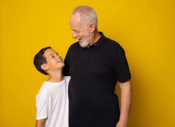 Grandfather and grandson smiling over yellow background