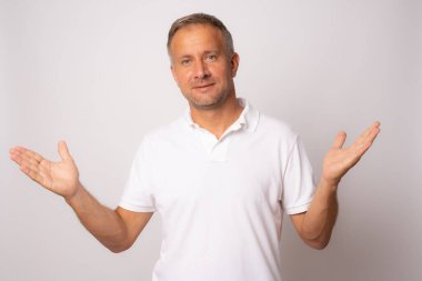 Soyutlanmış arka planda günlük giysiler giyen genç yakışıklı adam, soru sormayı ve kafa karıştırmayı sever..