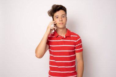 Beyaz arka planda izole edilmiş akıllı telefon kullanan günlük kıyafetli genç adam..