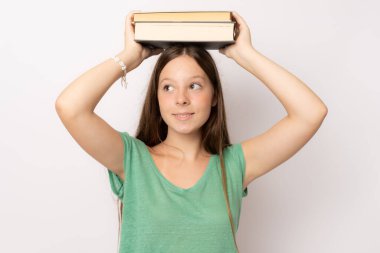 Kitapları tutan ve beyaz arka planda izole bir şekilde bakan neşeli bir kızın portresi.