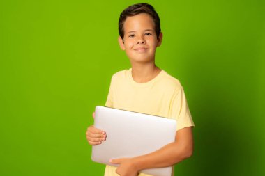 Yeşil arka planda izole edilmiş günlük giysili akıllı çocuk.