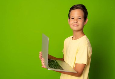 Yeşil arka planda izole edilmiş günlük giysili akıllı çocuk.