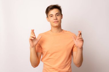 Genç adam beyaz arka planda izole edilmiş bir dilek diliyor.