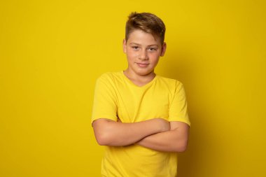 Neşeli çocuk sarı arka planda kollarını kavuşturdu..