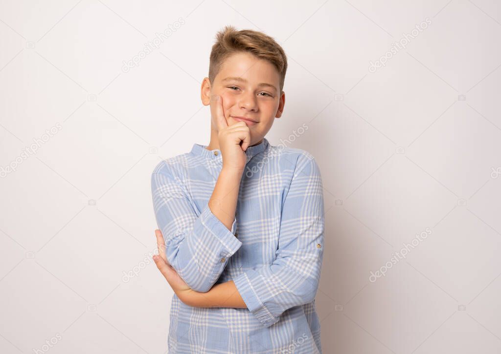 Pensive smiling boy in elegant shirt isolated over white background.