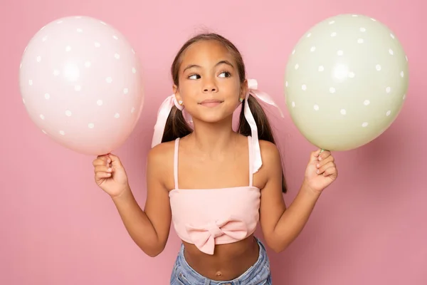 Renkli güzel küçük kız pembe arka planda izole edilmiş hava balonları..