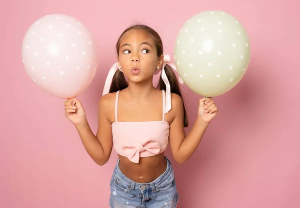 Renkli güzel küçük kız pembe arka planda izole edilmiş hava balonları..