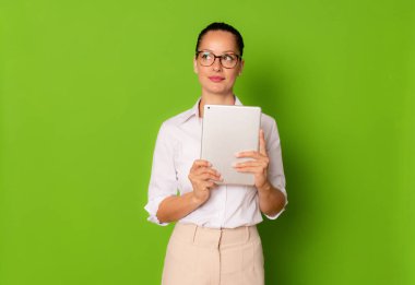 Yeşil arka planda izole edilmiş tablet kullanan genç iş kadını.