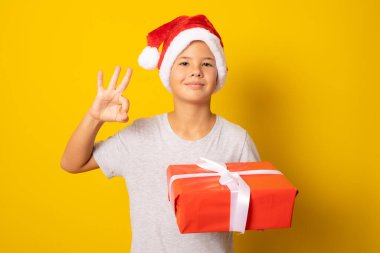 Mutlu bir çocuğun portresi. Elinde yeni bir hediye var. Sarı arka planda izole edilmiş işaret işareti..