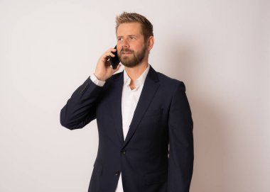 Genç gülümseyen iş adamı izole bir arka planda telefonla konuşuyor..