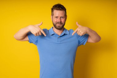 Yüzünde gülümseme ile kendinden emin görünüyorsun, kendini gururlu ve mutlu parmakları ile işaret izole arka plan üzerinde genç yakışıklı adam.