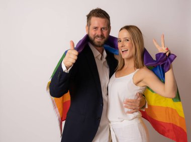 Genç LGBTQ çifti birbirlerine sarılırken bir arada duruyorlar..