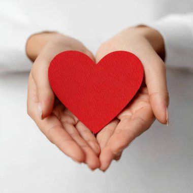 Kırmızı kalp kağıdını tutan kadın ellerinin yakın plan portresi. San Valentin Günü konsepti.