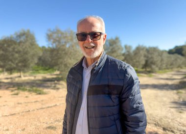 Parkta güneş gözlüğü ve kışlık giysiler takan gülümseyen son sınıf öğrencisi..