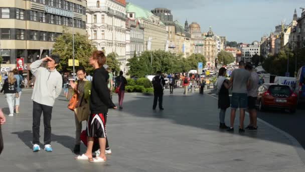 Place Venceslas avec les gens et les voitures de passage - bâtiments et la nature (arbres et buissons) - ciel bleu — Video