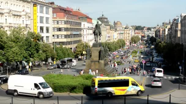 Wenceslas Square with people and passing cars - buildings and nature(trees and bushes) - blue sky — Stock Video