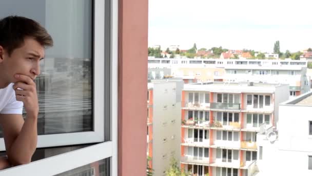 Homem janela aberta e olhando para fora da janela na rua movimentada - cidade (bloco de apartamentos) no fundo — Vídeo de Stock