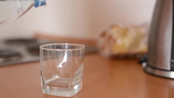 Gieten van water in een glazen fles - in de keuken (keuken eenheden) — Stockvideo