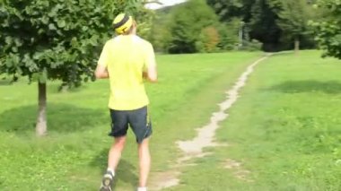 adam spor - koşma - adam ısınma ve sonra başlangıç steadicam - ağaçları ile yeşil çimen - çalışan