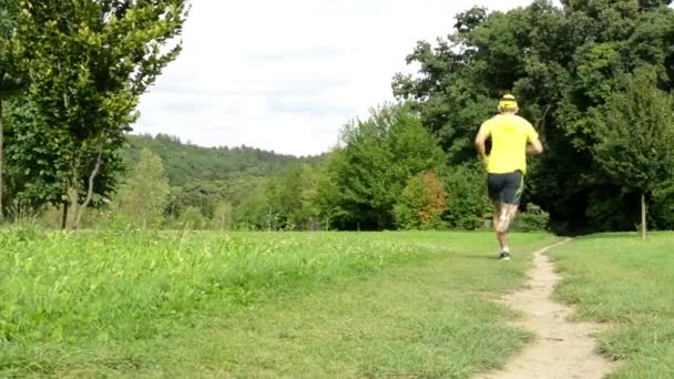 Esportes de homem - corrida - parque (árvores e grama) - céu nublado - controle deslizante — Vídeo de Stock