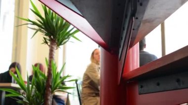 genç kadın merdivenlerden yukarı gidiyor - diğer insanlar içinde arka plan ve konuşma ve içecek kahve oturmak