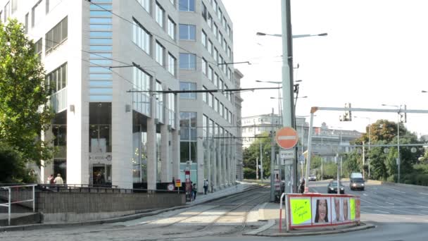 Modern building with trams and passing cars on the urban street - nature (trees) — Stock Video