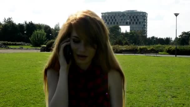 Young attractive woman goes in park  - nature with modern building in the background - woman telephone - nature — Stock Video