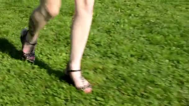 Mladá atraktivní žena jde v parku - příroda s moderní budovy v pozadí - záběr z nohou — Stock video