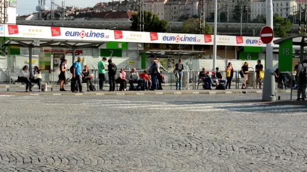 Estação terminal de ônibus - as pessoas esperam pelo ônibus - pessoas pendulares - edifícios em segundo plano — Vídeo de Stock