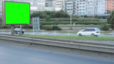 Billboard in de stad in de buurt road - groene scherm - gebouw en het doorgeven van auto's op achtergrond