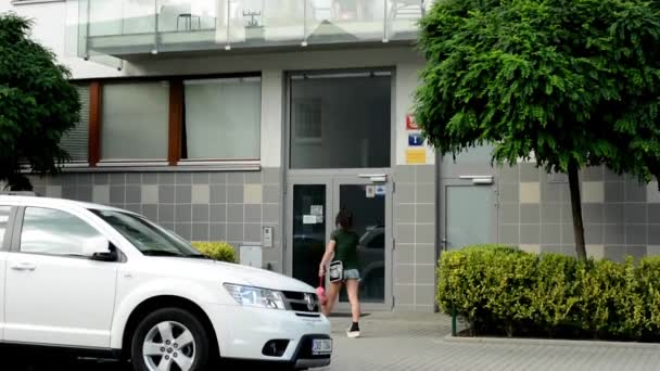 Entrada en la casa moderna (pisos) exterior - coche aparcado - mujer entra en el interior — Vídeos de Stock