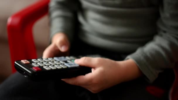 Niño juega con un controlador de TV - niño se sienta - detalle del controlador de TV remoto — Vídeo de stock