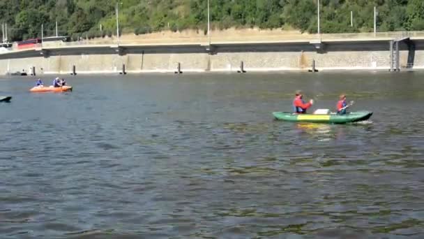 Personas a bordo y remando - piragüismo - barcos en el río (Moldava) - ciudad (edificios) en el fondo - puente - soleado — Vídeo de stock