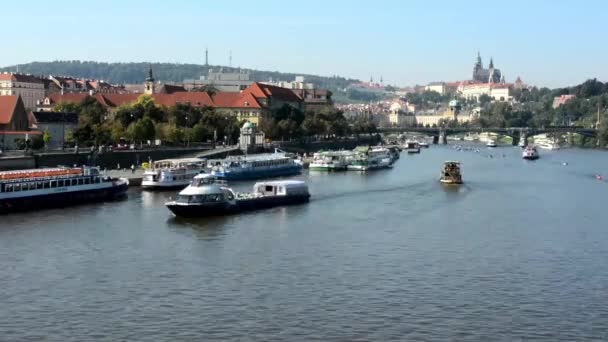 Boote auf dem Fluss (Moldau) - Stadt (Gebäude) im Hintergrund - Prager Burg (Hradcany) - Zeitraffer - sonniger (blauer Himmel) - Autos und Bäume — Stockvideo