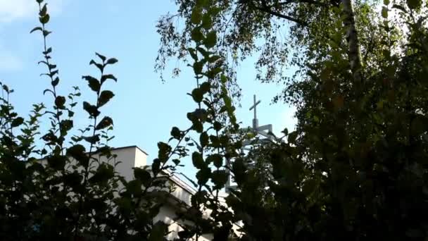 Naturaleza (árboles) - iglesia moderna (torre con un crucifijo) - cielo azul — Vídeos de Stock