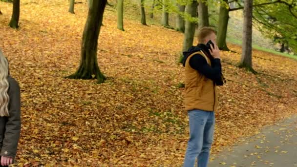 Jeune couple modèle amoureux - couple heureux dans le parc d'automne (nature) - femme au téléphone et homme au téléphone (couple appelant par smartphone) - concept (homme et femme sont à la recherche) - rencontres - couple se tenant la main 