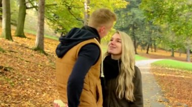 Genç çift aşık model - sonbahar - çift (erkek ve kadın) söz - park(nature) adam kadın - mutlu çift - çift öpüşme için bir hediye verir