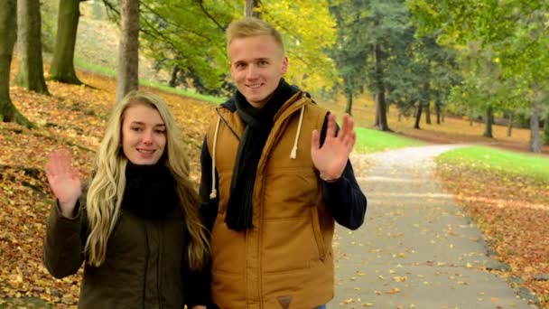 Joven modelo de pareja enamorada - otoño parque (naturaleza) - pareja ola con las manos - feliz pareja — Vídeos de Stock