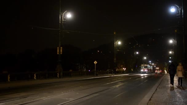 Nacht straat met mensen en auto's en tram - brug met lampen — Stockvideo