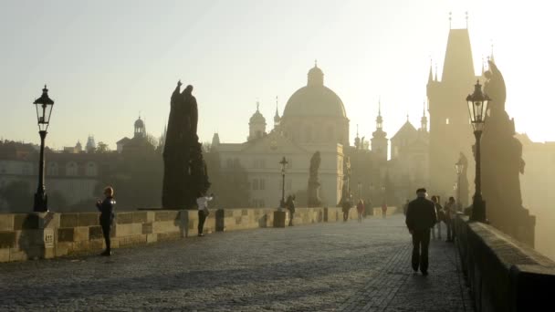 Puente de Carlos con la gente a pie - amanecer - ciudad - niebla de la mañana - edificios con estatuas - empedrado de la acera — Vídeo de stock