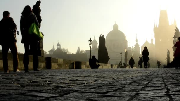 Charles bridge with people walk - sunrise - city - morning mist - buildings with statues - sidewalk cobblestone — Stock Video