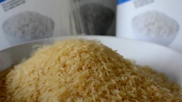Ρίχνει το φυσικό ρύζι στο πιάτο - κουτιά με άσπρο ρύζι στο παρασκήνιο — Αρχείο Βίντεο
