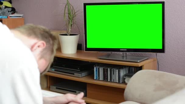 Man watches TV(television) - green screen - man laughs — Stock Video