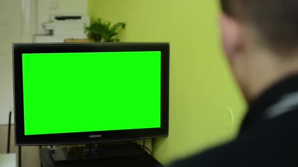 Чоловік дивиться телевізор (телебачення) - зелений екран — стокове відео