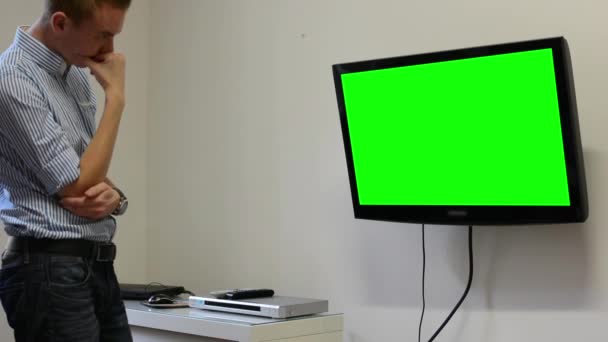 El hombre ve la televisión (televisión) - pantalla verde - el hombre expresó tristeza — Vídeos de Stock