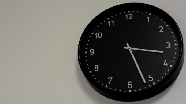 Black clock on the white wall — Stock Video